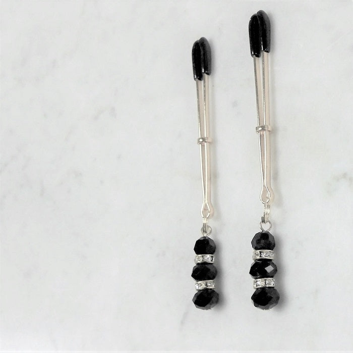 Elegante tepelklemmen met zwarte rubberen uiteinden en decoratieve kralen met strass